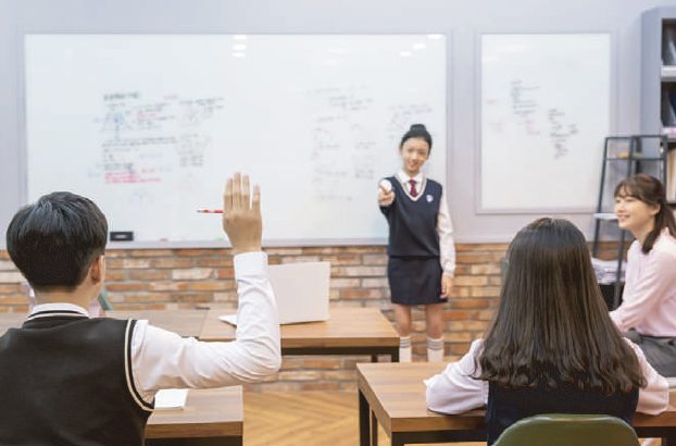 칠판 앞에서 풀이를 발표하고 친구들이 손을 들어 질문하는 모습